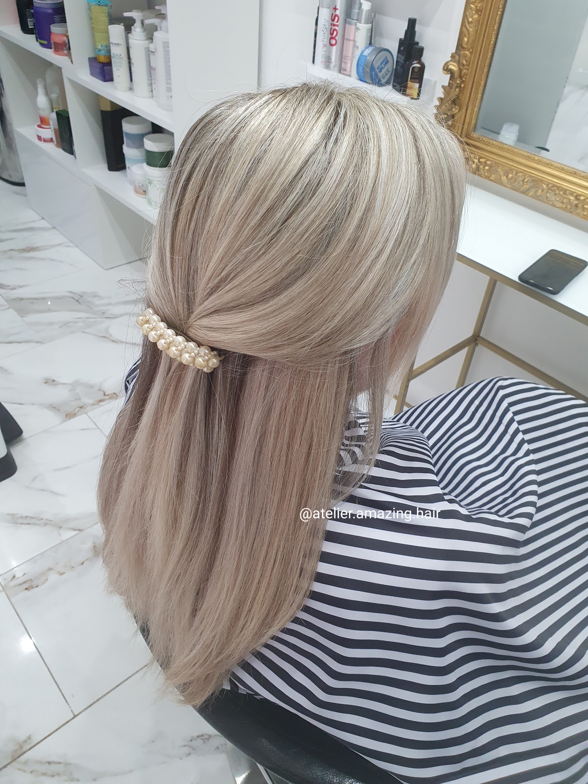 Lang asblond haar, half opgestoken met een parelspeld