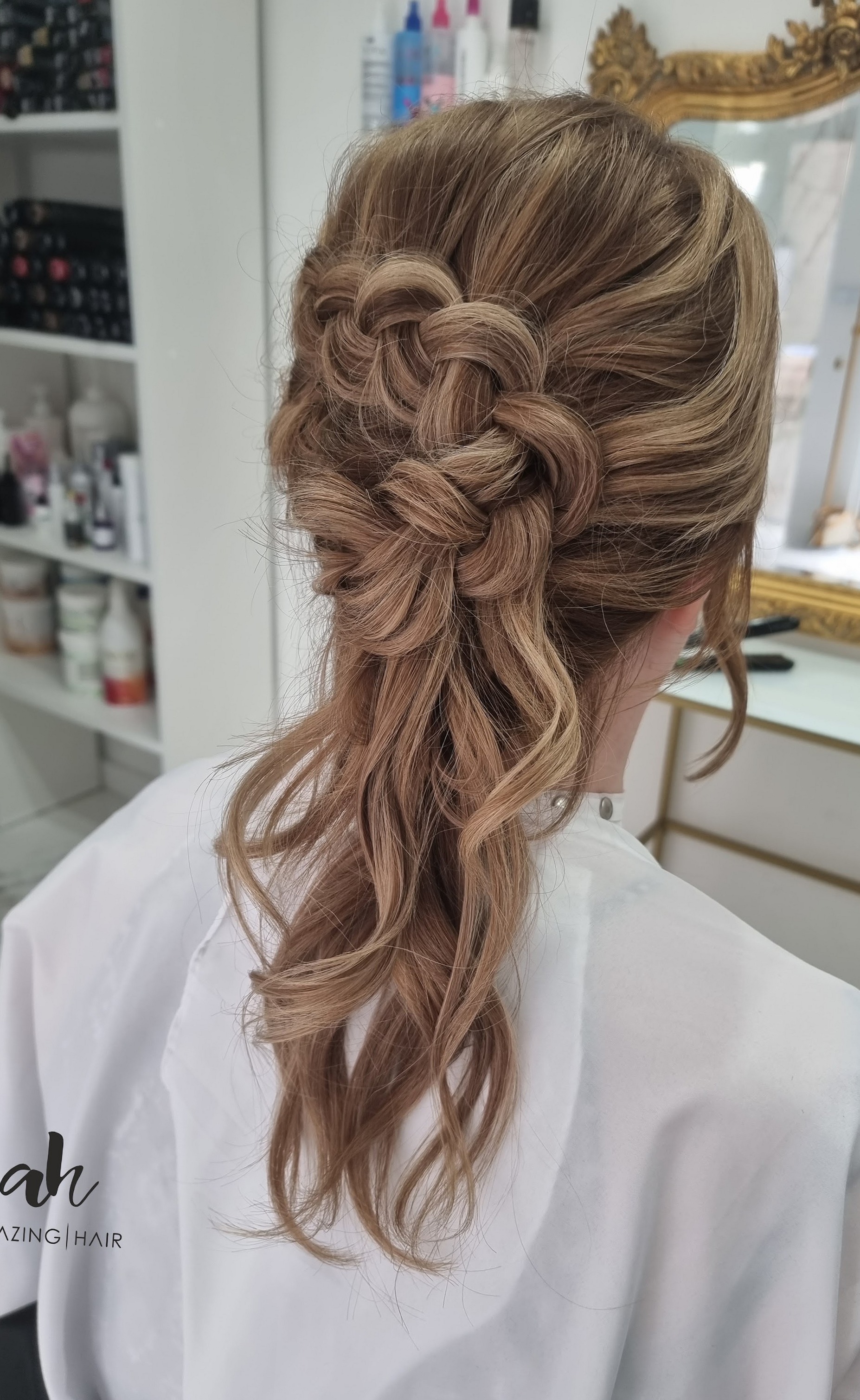 Losse vlecht in een halfopgestoken kapsel, met de cape met het ah-logo van de salon